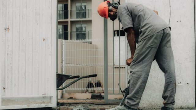 Man in hard hat operating a jackhammer on an outdoor construction site.