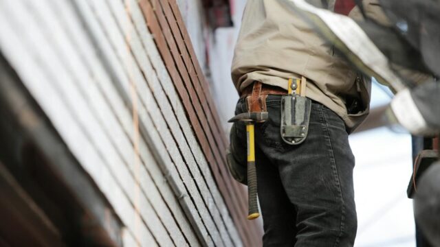 Close-up of a construction worker with hammer and tools, focused on the job.